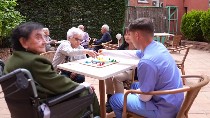 Nurse, daughter and senior women playing a board game in the garden of a nursing home, enjoying leisure time and social interaction