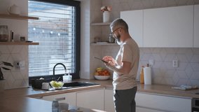 Mature man adjusting windows blind in the kitchen by tablet. - Powered by Shutterstock - Get 15% off with code: PIKWIZARD15