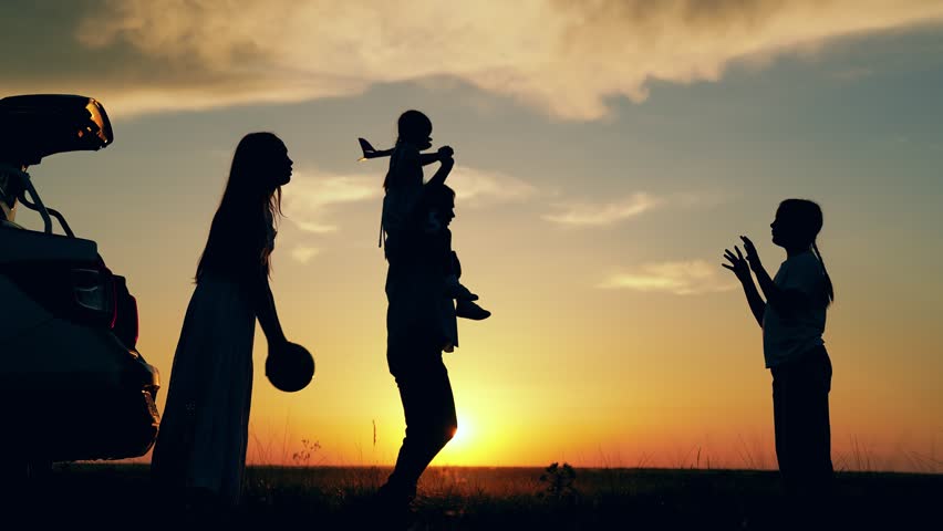 Parents children daughters have fun sunset. Happy family travels by car. Big family, Travel by car. Mom dad children stopped at campsite by car. Mother father play with children ball toy airplane. Kid