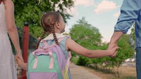 Girl child with parents go to school. Concept of children education. Child daughter with backpacks, father mother go to school holding hands. Happy family. Mother father take child to school on street - Powered by Shutterstock - Get 15% off with code: PIKWIZARD15
