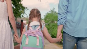 Girl child with parents go to school. Concept of children education. Child daughter with backpacks, father mother go to school holding hands. Happy family. Mother father take child to school on street - Powered by Shutterstock - Get 15% off with code: PIKWIZARD15