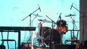 Drum set and other musical equipment near screen with video art