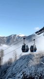 Cable cars glide above a frosty forest with snow-covered mountains and clouds. Gabala, Azerbaijan - Powered by Shutterstock - Get 15% off with code: PIKWIZARD15