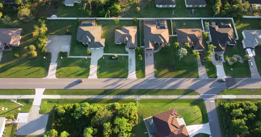 Small town rural street traffic with driving cars in North Port, Florida. American suburban landscape with private homes in quiet residential area.