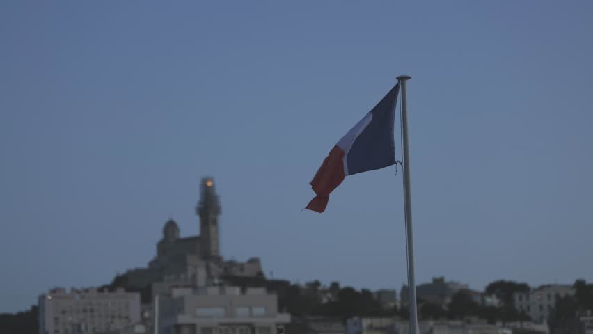 French flag at evening, Notre Dame de la Garde in the background, Marseille France