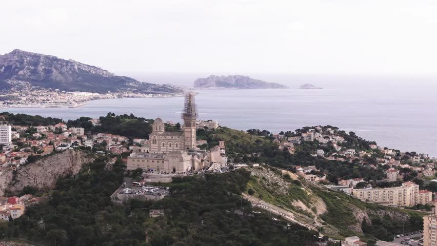 Drone spin around Notre Dame de la Garde from far, French landscape in background