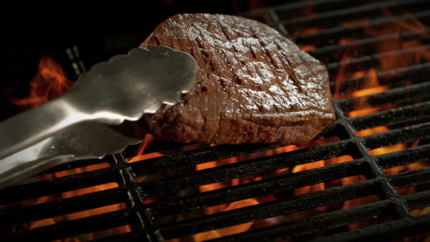 Super Slow Motion Shot of Flipping Beef Steak Meat on Grill with Camera Motion at 1000fps.
