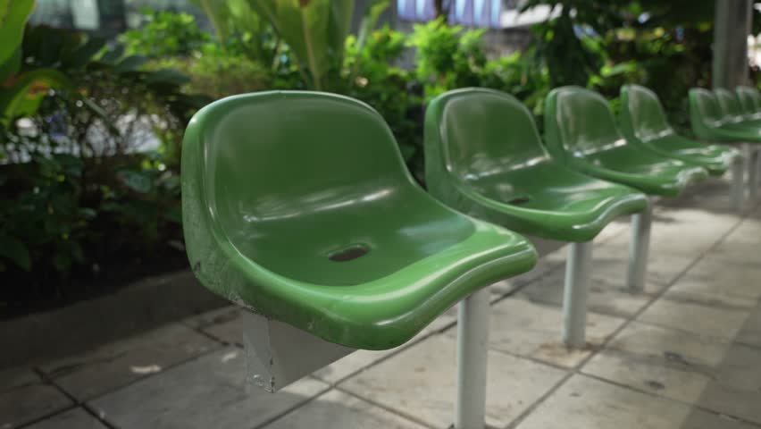 Close up of row empty green plastic seats on bus station with city street background and copy space