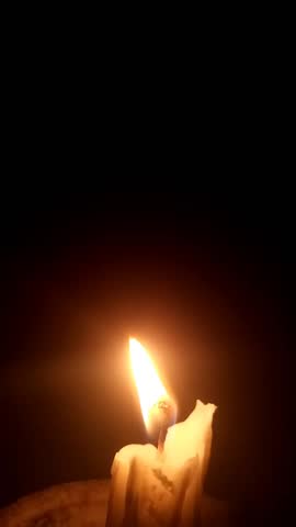 A small candle flame flickers gently in the darkness, creating a peaceful, warm ambiance. Ideal for themes of meditation, spirituality, relaxation, or romantic atmosphere.
