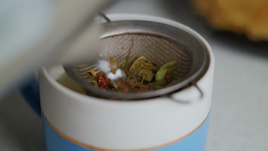 Boiling water being poured over herbs for calming, natural homemade tea brew