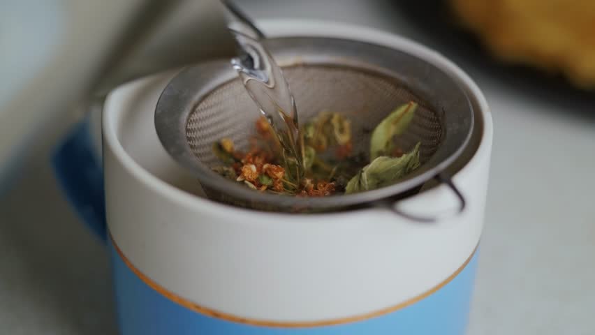 Close-up of herbal tea infusion with loose leaves steeping in a mesh strainer