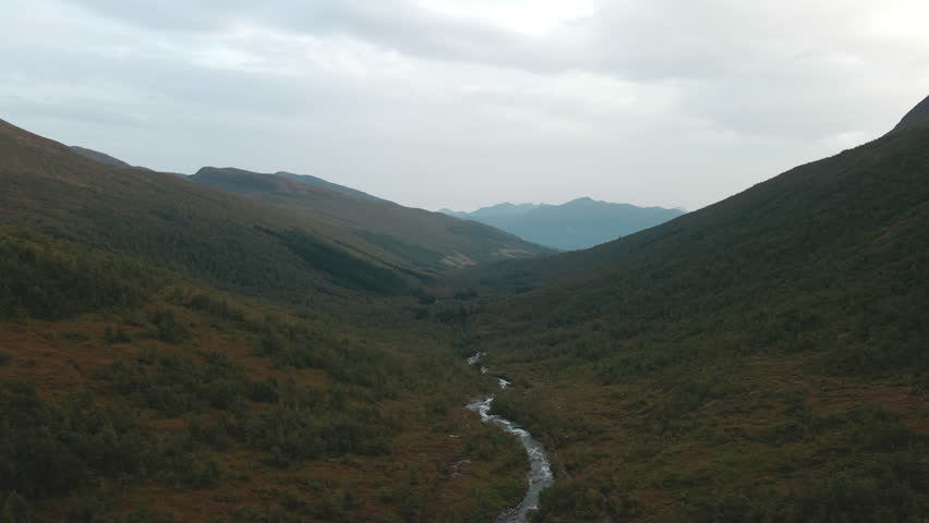 Drone flying over a valley with a river running down in the middle