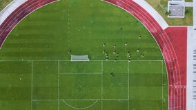 Aerial view of a soccer training session on a green football field with players practicing drills. Running track and goalpost visible. Sports practice and teamwork concept - Powered by Shutterstock - Get 15% off with code: PIKWIZARD15