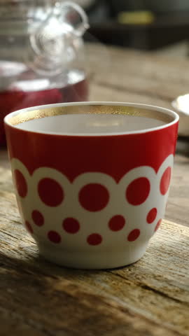 Vertical video. Tea party. Cup of red hot hibiscus tea on wooden table. Morning breakfast.
