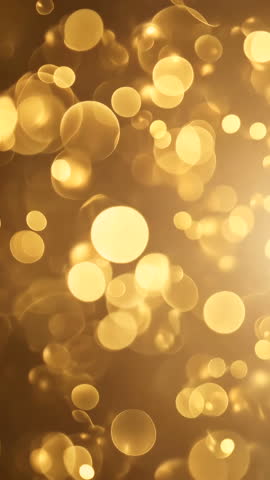 Golden particles floating gently creating a magical bokeh effect. Vertical video.