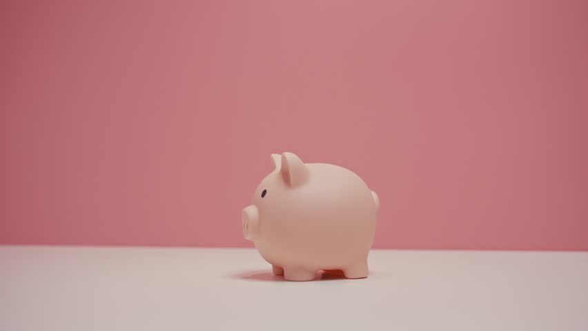 Close up of hand dropping an baht coin into a pink piggy bank. Financial and Business Safety Concept.