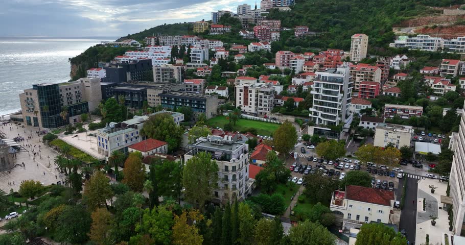 Coastal residential buildings and hillside homes near Budva Old Town in Montenegro. Aerial view, pan left