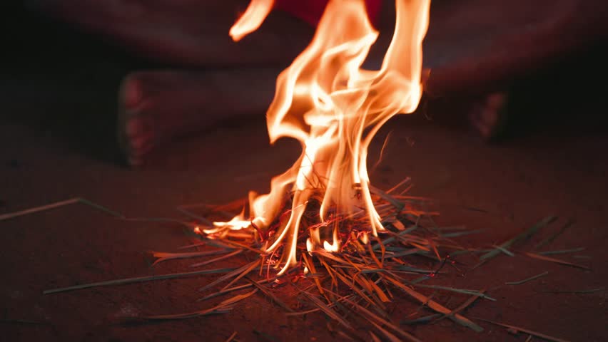 An aborigine in a loincloth makes fire in the traditional way, striking sparks on tinder, lighting a hearth in a hut. An ancient way of making fire in slow motion