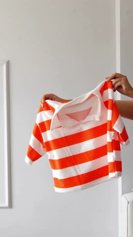 4K Video of Woman Showing Orange and White Striped Top Against Plain Background – Fashion Apparel Showcase