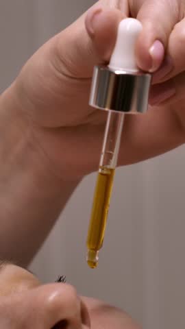 The beautician applies vitamin C serum with antioxidants against pigmentation and wrinkles to a woman's face. Professional care in a beauty salon