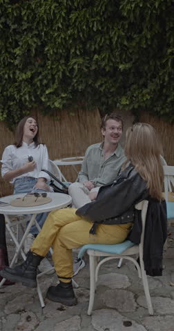 Friends hanging out at an outdoor cafe, laughing and enjoying each other