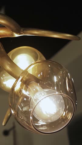 Vertical shot. Close-up of a chandelier providing a warm glow in a beautiful modern interior design against a dark background