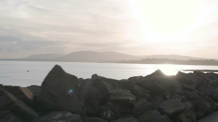Beautiful sunset over calm waters near rocky shoreline in Carrickfergus