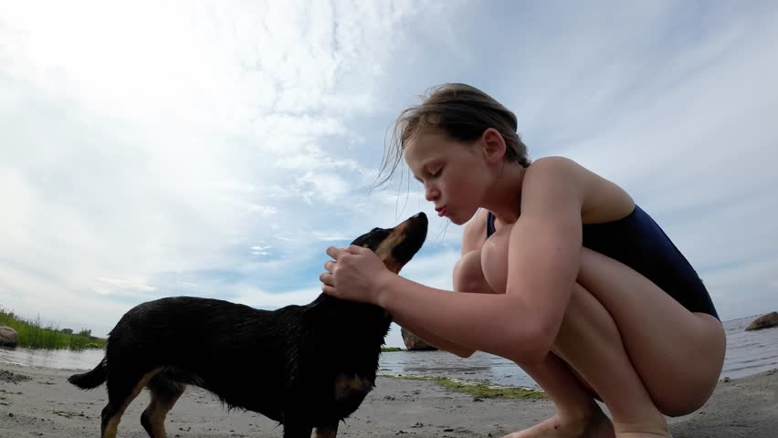 Girl pets a dog dachshund on the beach.