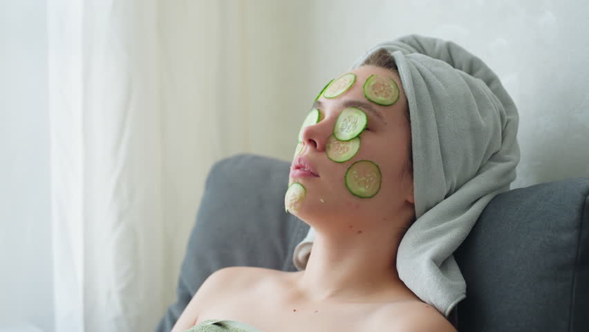 Close-up view of woman with cucumber slices placed on her face while relaxing, she enjoys a soothing self-care moment, feeling calm and rejuvenated with cucumber mask for skin refreshment