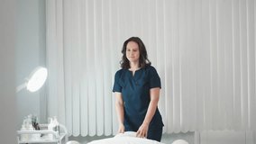 Skin therapist in navy uniform opens door with warm smile to welcome client, then gestures toward cream massage chair in bright white room, creating professional atmosphere before facial treatment - Powered by Shutterstock - Get 15% off with code: PIKWIZARD15