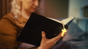 Woman holding rosary and reading Bible in bed, glowing cross, power of prayer - Powered by Shutterstock - Get 15% off with code: PIKWIZARD15