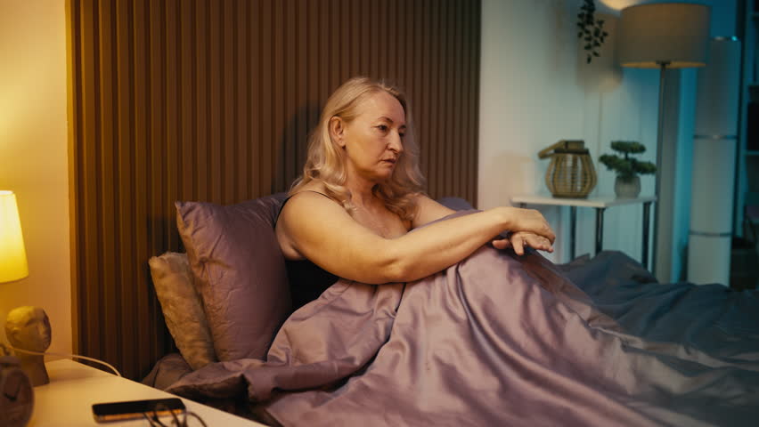 Depressed middle-aged female crying alone in bed, relationship struggles