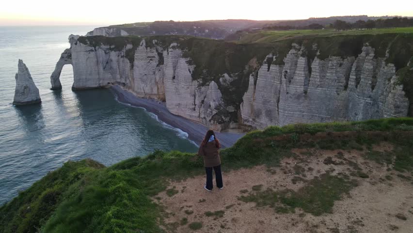 Iconic chalk cliffs and turquoise waters of Etretat glow under sunlight, showcasing Normandy