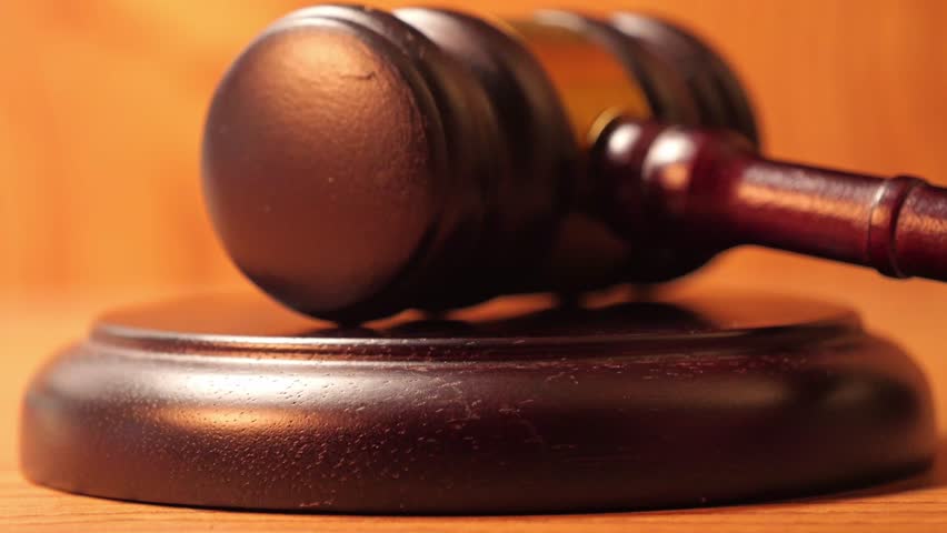 Slow-motion cinematography of a gavel's impact, as seen in depictions of judicial proceedings or auction events.