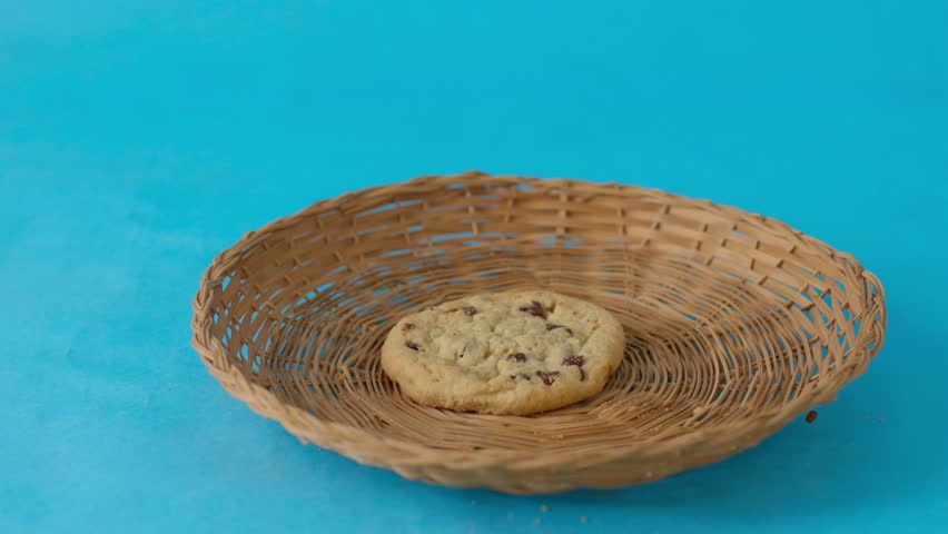 A cookie sits in a basket on a blue background