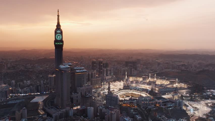 A breathtaking sunrise illuminating the Abraj Al-Bait Clock Tower and Grand Mosque in Mecca, surrounded by the sprawling city and mountains in a serene morning view