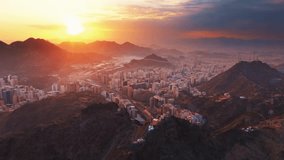 Mecca, Saudi Arabia - A breathtaking aerial view of Mecca city at sunrise, showing urban architecture surrounded by majestic mountains under a golden sky - Powered by Shutterstock - Get 15% off with code: PIKWIZARD15