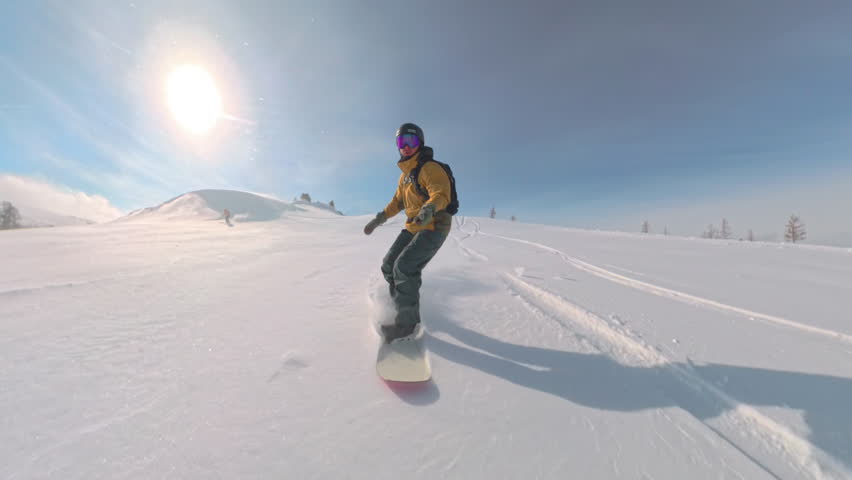 Free spirit snowboarding in wild mountain forest flying through powder snow with motion blur snow spray and deep turns among snowy trees in beautiful winter light