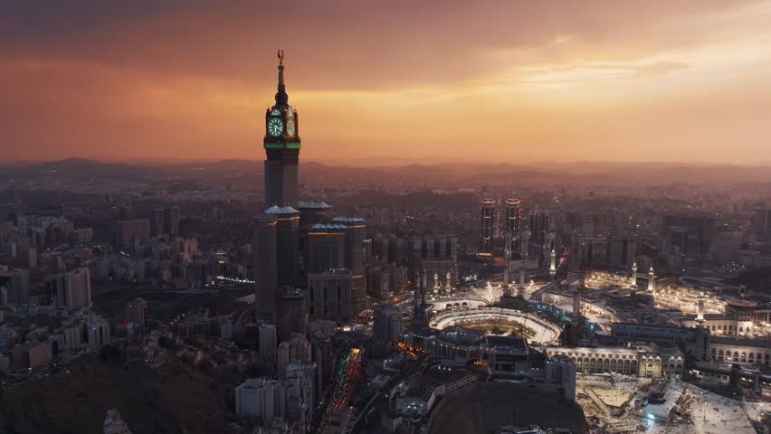 Aerial view of the illuminated Grand Mosque and Abraj Al-Bait Clock Tower in Mecca at dusk, showcasing the holy city’s vibrant atmosphere as night falls