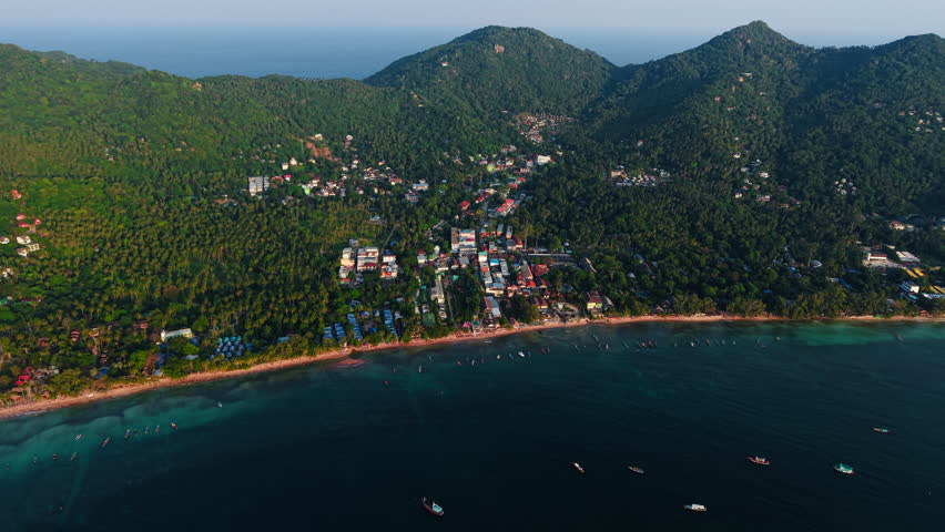 Scenic aerial panorama revealing the coast of Koh Tao Island with turquoise waters near the forests with yachts near the coast in Thailand