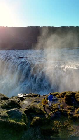 Experience the powerful beauty of Dettifoss in Iceland, one of Europes largest waterfalls, surrounded by mist and stunning landscapes. Visitors marvel at its cascading waters amid vibrant hues.