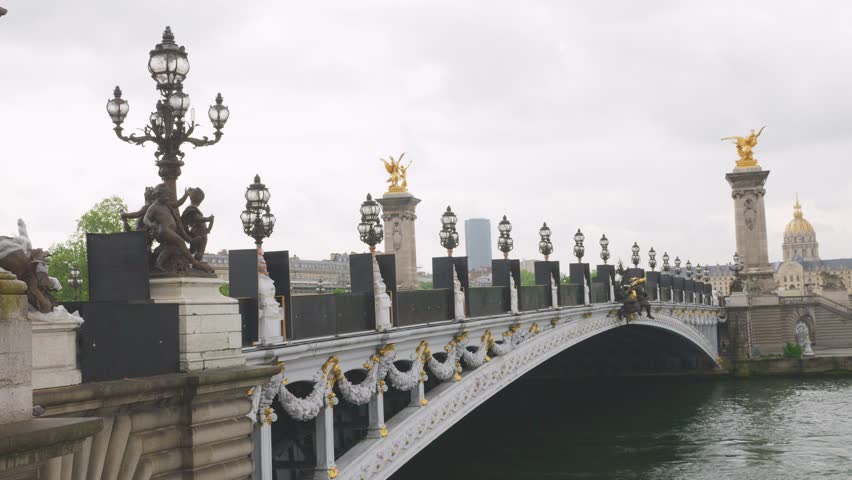 View of the the Pont Alexandre III bridge with elegant decor and beautiful street lamps over the Seine River and the House of Invalides on the left bank in Paris, France.