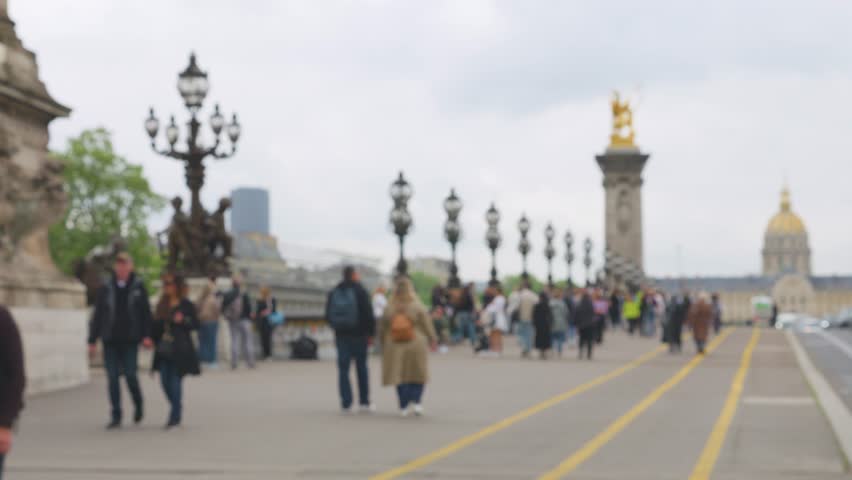 Flow of cars and pedestrians crosses the Seine River on the Pont Alexandre III bridge in Paris, France. Out of focus.