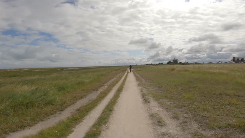 Theme is bicycle trip through north of France, region of Brittany and Normandy. POV view of cyclists on a gravel bike and walk path along the ocean in Saint-Malo. Cycling route in Mont Saint-Michel
