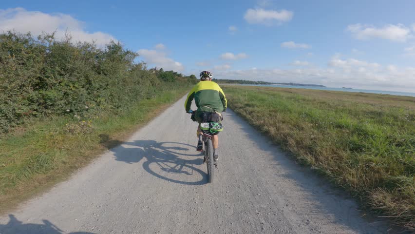 Theme is bicycle trip through north of France, region of Brittany and Normandy. POV view of cyclists on a gravel bike and walk path along the ocean in Saint-Malo. Cycling route in Mont Saint-Michel