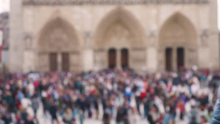 Crowd of tourists at the Place Jean-Paul II near the Catholic cathedral church Notre-Dame de Paris on the island Ile de la Cite, 4th arrondissement of Paris, France. Out of focus.