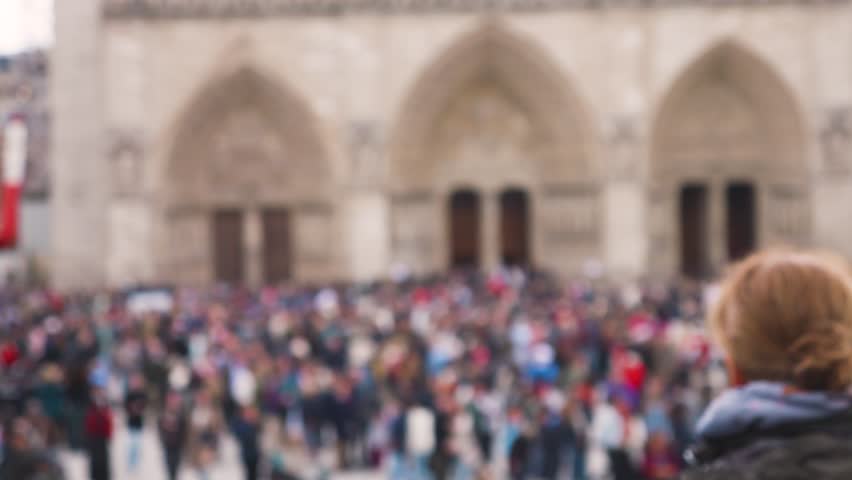 Crowd of tourists at the Place Jean-Paul II near the Catholic cathedral church Notre-Dame de Paris on the island Ile de la Cite, 4th arrondissement of Paris, France. Out of focus.