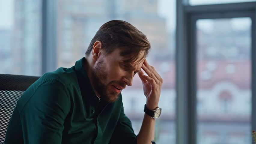 Overloaded entrepreneur thinking business project feeling tension in modern light office interior closeup. Anxious businessman looking solutions to problem. Bearded businessman worried papers mistake.