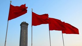 red flags flying in front of the monument in the centre of tiananmen square Beijing China