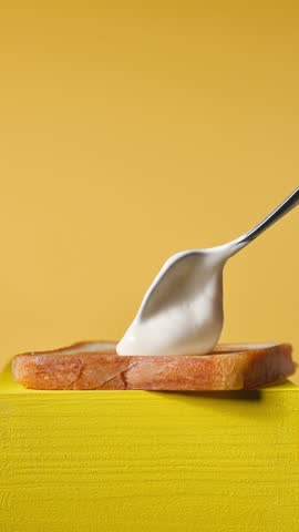 cook put mayonnaise on fresh toasted bread slice on yellow wooden board for making club sandwich, food closeup. Process of making healthy meal